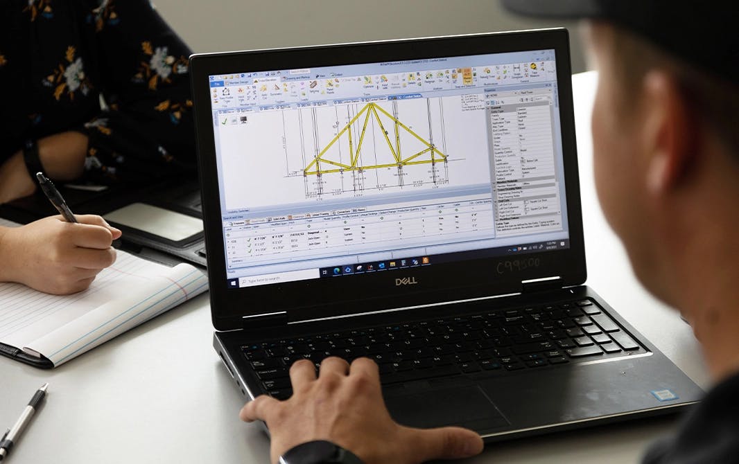 Man looking at roof truss design plans on a laptop computer.
