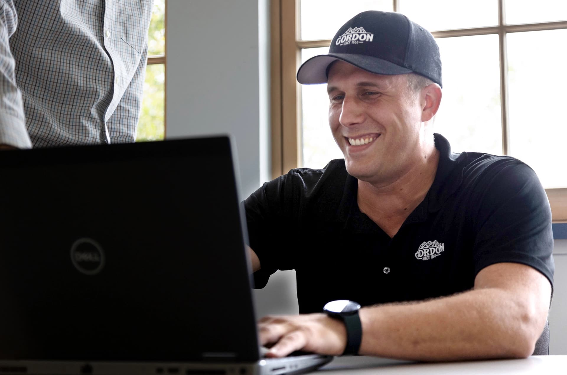 Smiling man filling out a job application on a laptop computer.