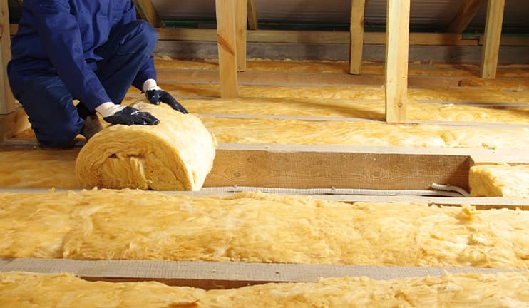 Worker installing insulation in an attic.