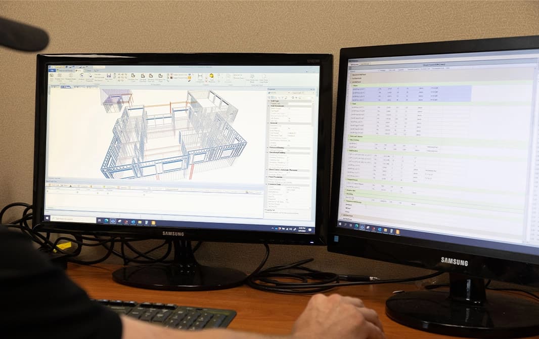 Computer monitors with 3D renderings of construction site.