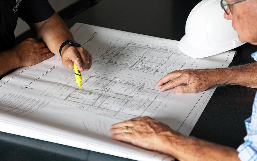 Home building experts carefully looking over a floorplan.