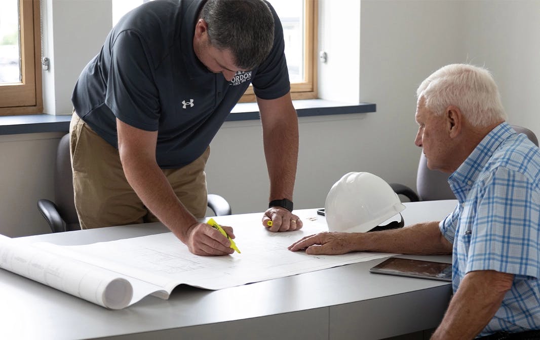 Two men making notes on a home blueprint.