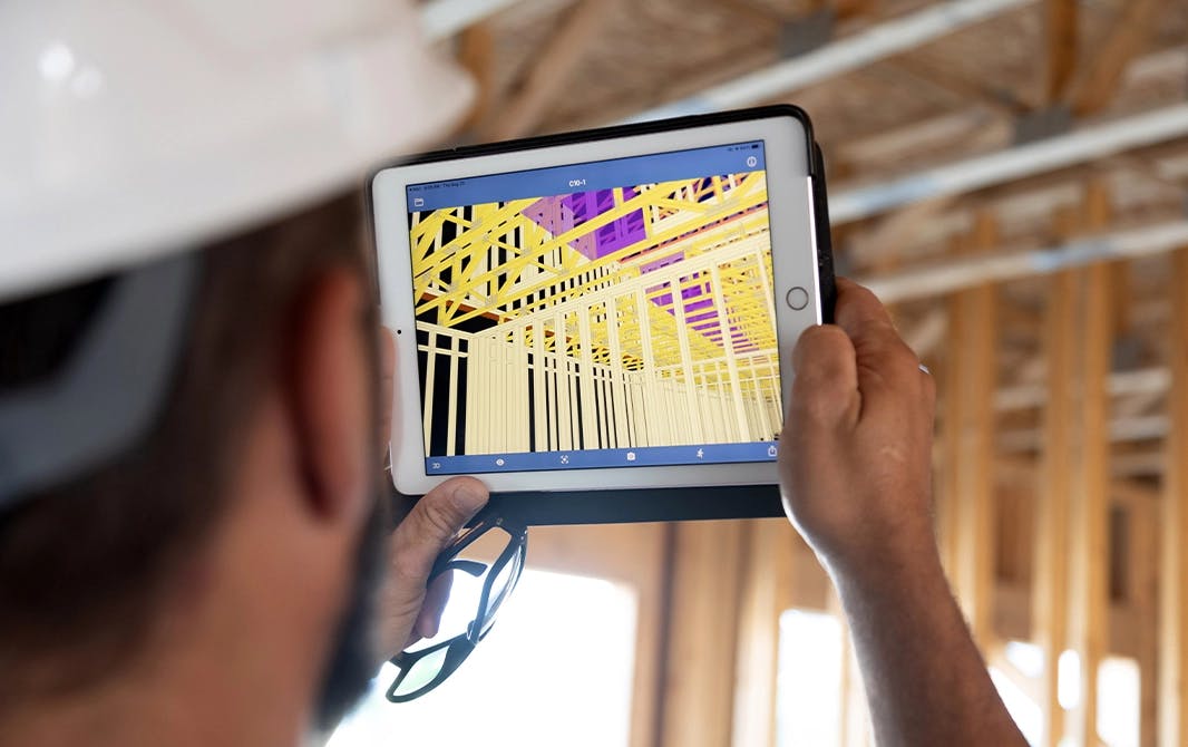 Man looking at a 3D blueprint on a tablet while on a building site.